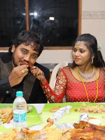 The bride feeds the groom a piece of chicken, a sweet and intimate moment during their celebration.