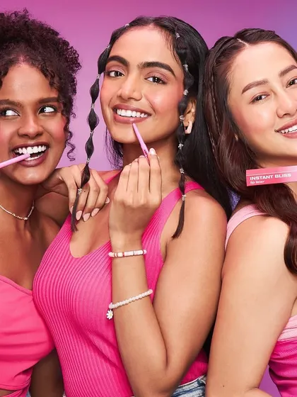 A fun and engaging shot for Joyology Beauty, with models applying lip and cheek tints. The makeup is fresh and coordinated in shades of pink, demonstrating the product's ease of use and vibrant color payoff.