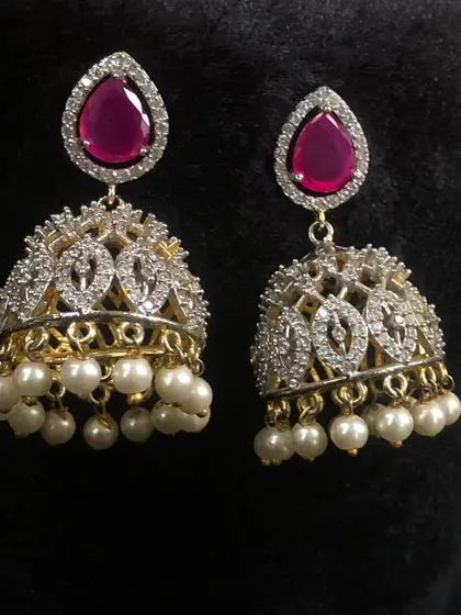 A pair of elegant jhumkas with a ruby top and CZ-studded dome. These are a perfect blend of traditional and modern design.