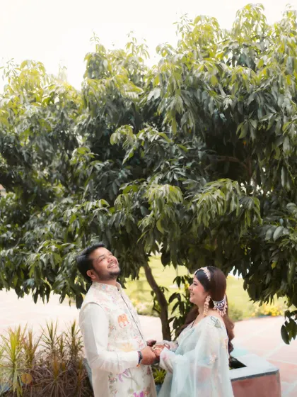 A candid and happy moment between a couple under a large tree during their Haldi ceremony. Their joyful expressions capture the relaxed and celebratory mood of the day.