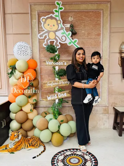 A mother and son pose next to a custom safari-themed directional sign and a balloon column.