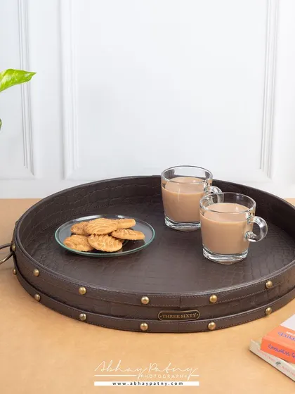 This image showcases a large leather serving tray in a home setting. The styling with tea and biscuits demonstrates a practical use case and creates a warm, inviting atmosphere.