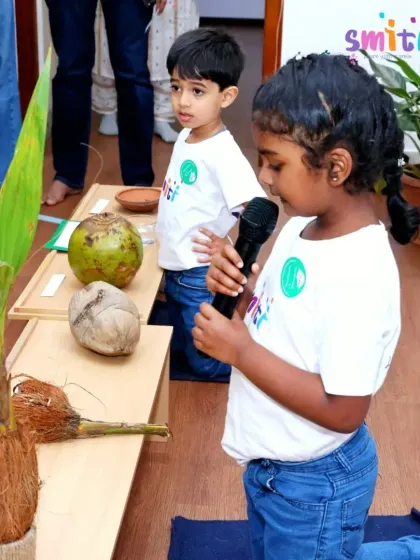 A young girl confidently speaks into a microphone, explaining the life cycle of a coconut to her family. Events like these build public speaking skills and self-assurance.