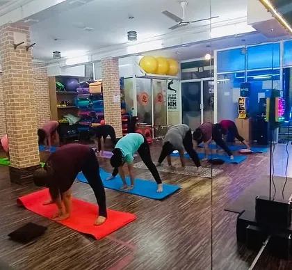 A wide shot of our studio during a forward fold sequence. Our spacious, clean studio with wooden floors provides a perfect setting for your practice.