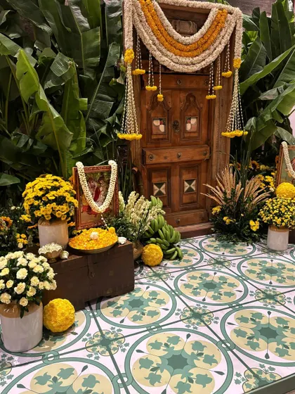 A traditional entryway decorated with marigolds, banana leaves, and a beautiful patterned floor.
