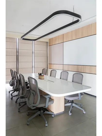 The main conference room at Thalia, designed for focus and clarity. The space features a large whiteboard wall, clean lines, and a modern overhead light fixture that illuminates the entire table.