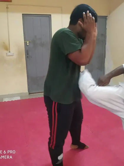 A student practices defending against a body kick. Learning to absorb and block strikes to the torso is a fundamental part of our self-defense training.