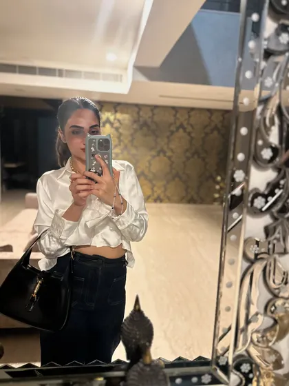 A mirror selfie in a chic white satin shirt and dark jeans.
