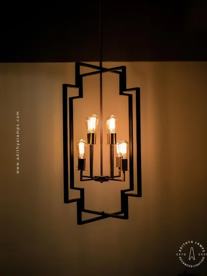 Inspired by Art Deco design, this hanging fixture features a strong geometric black frame with exposed vintage-style filament bulbs. The combination of black and warm gold tones provides a sophisticated, retro feel for dining areas or entryways.