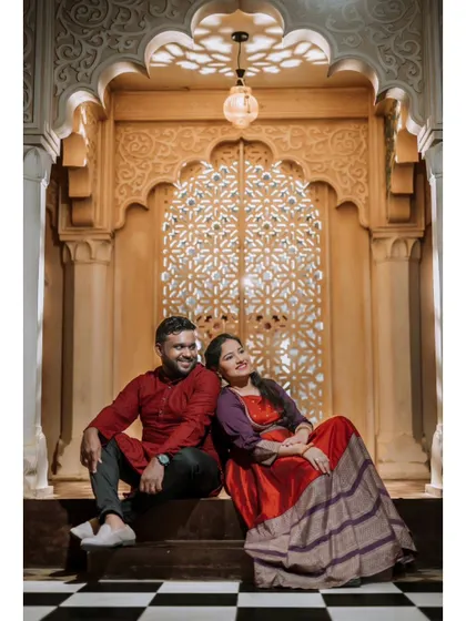 A serene and romantic portrait of a couple sitting in front of an ornate, beautifully lit archway.