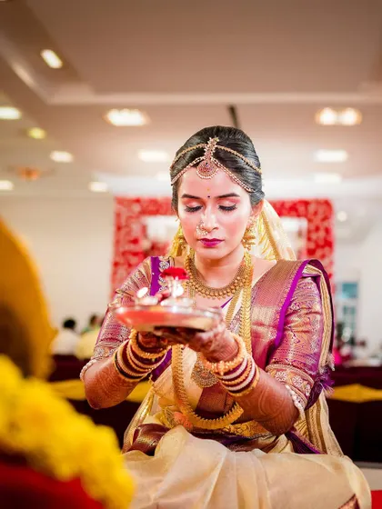 A serene portrait of the bride performing a ritual during her wedding ceremony.