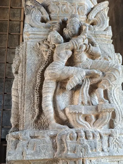 A sculpture of a couple in a loving embrace on a pillar at Bale Mantapa. The details, like the woman's long plait, are captivating.