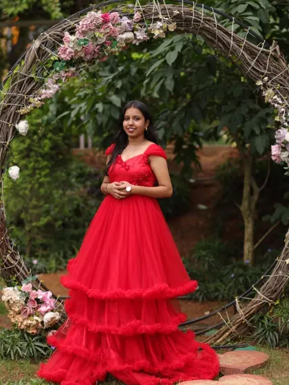 A happy client looking like a princess in a stunning red tiered gown for her pre-wedding photoshoot.