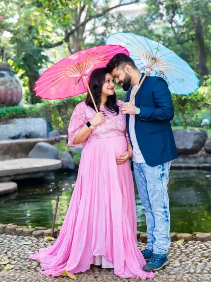 A playful and colorful shot using pink and blue umbrellas. This is a fun way to hint at a gender reveal or simply add a vibrant and joyful element to the maternity shoot.