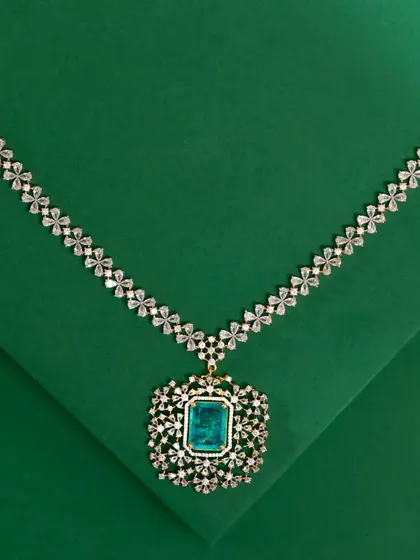 For a touch of modern luxury, I offer pieces like this stunning American Diamond and emerald-style necklace. The brilliant-cut stones are set in a floral pattern, leading to a magnificent centerpiece that makes a bold statement. This is the perfect accessory for cocktail parties or formal receptions.