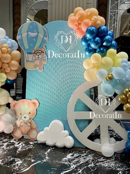 A photo corner combining a rippled arch backdrop, a wheel prop, and cute teddy bear cutouts.
