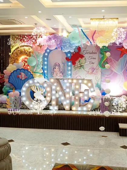 The main stage for the "Under the Sea" party, featuring a beautiful backdrop with mermaid tails, shells, and sea creatures, all in a dreamy pastel palette.