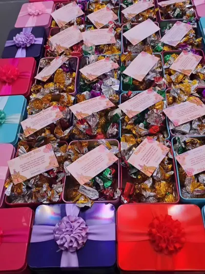 A colorful array of budget-friendly chocolate boxes for a birthday party. Each tin is filled with assorted chocolates and includes a personalized thank you card.