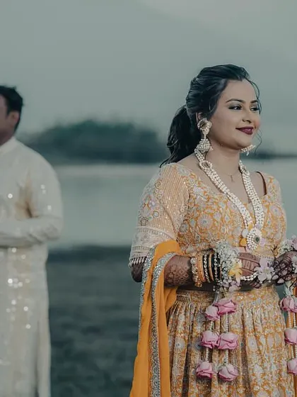 A serene pre-wedding shoot by the water. The bride is wearing our custom jewellery set with delicate pink and yellow floral kalire.