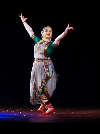 A joyful, leaping pose from Meera Sreenarayanan's recital, showcasing her vibrant stage presence.
