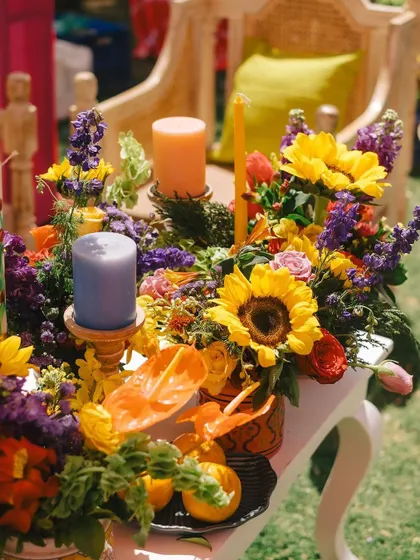 A lush centerpiece for an outdoor event, featuring sunflowers, lavender, and a mix of colorful blooms. The arrangement is vibrant and cheerful, perfectly suited to the sunny setting.