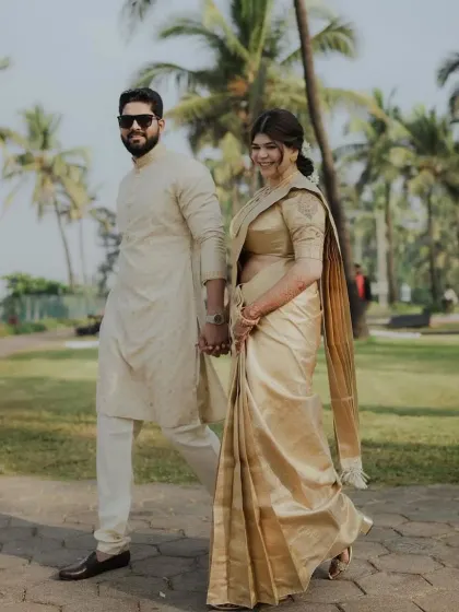 A Maharashtrian bride walking hand-in-hand with her partner. The pre-pleated silk saree drapes beautifully, allowing for natural movement.