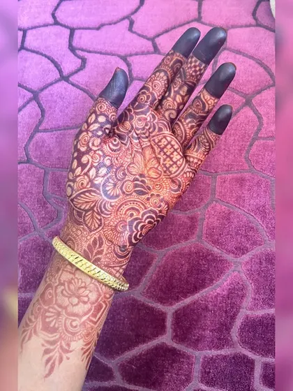 This is what I call 'stain goals'. A fully developed, dark henna stain on the palm, showcasing a mix of floral and paisley patterns. The dark fingertips and rich color are exactly what you want for a special occasion.