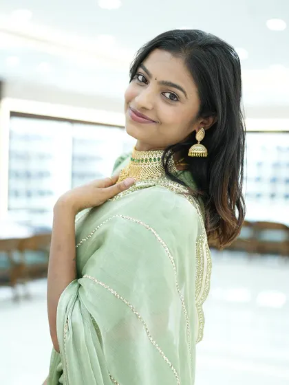 A smiling Sonu trying on a gold choker, showing how our outfits can be styled for different looks.