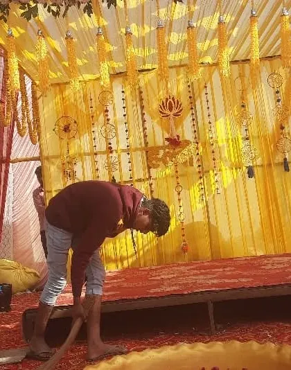 This image shows my team at work, setting up a Haldi mandap. You can see the yellow fabric drapes and marigold hangings coming together to create the final festive look.