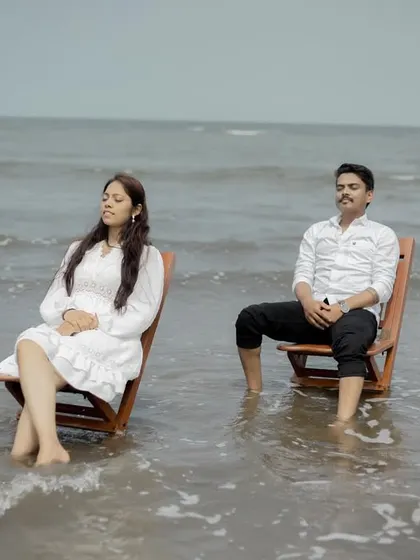 A serene and slightly playful moment with the couple relaxing in chairs as the tide comes in, capturing a unique beach experience.