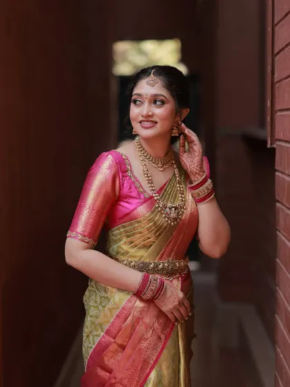 A candid shot of the bride, showing how her makeup looks natural and beautiful in soft light. The hairstyle is a classic South Indian braid, neat and elegant.