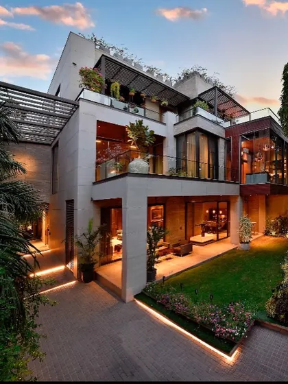 This modern home in Gurgaon showcases how to create a private sanctuary within an urban context. The design uses stacked volumes, terraces, and large glass openings to maximize light and green views, creating a warm, luxurious space that steps back from the city's pace.