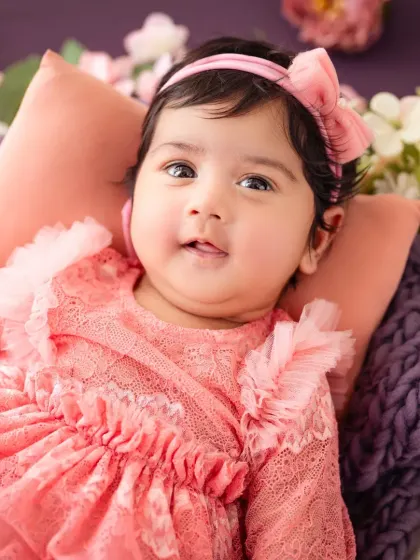 This little princess is pretty in pink for her milestone photoshoot, looking right at the camera.