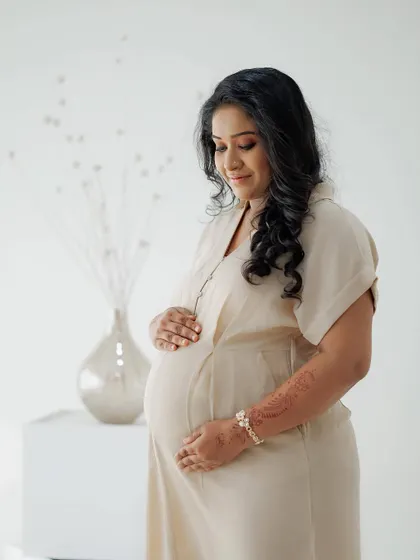 A side profile showcasing the beautiful baby bump. The makeup is soft and glowing, with defined eyes and a subtle lip color, ensuring the mom-to-be looks and feels her best.
