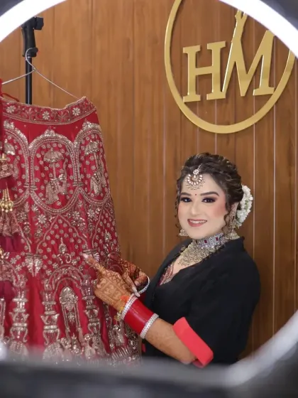 A lovely shot of the bride getting ready, admiring her stunning red wedding lehenga. This moment of anticipation and admiration is a beautiful part of the wedding story.