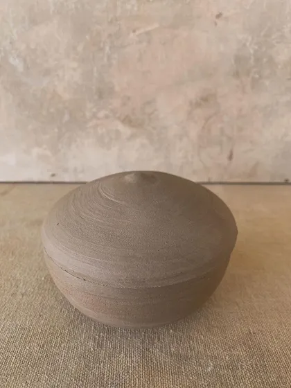 A perfectly round, unglazed lidded jar, like a smooth river stone. This piece is incredibly satisfying to hold.
