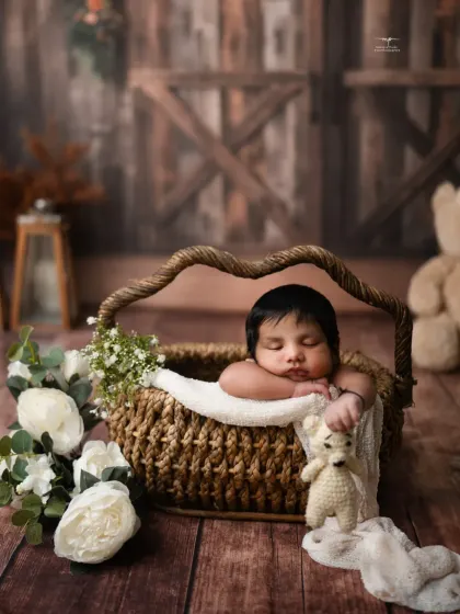 Tucked into a woven basket with a little teddy, this newborn looks so cozy and content in our rustic barn setup.