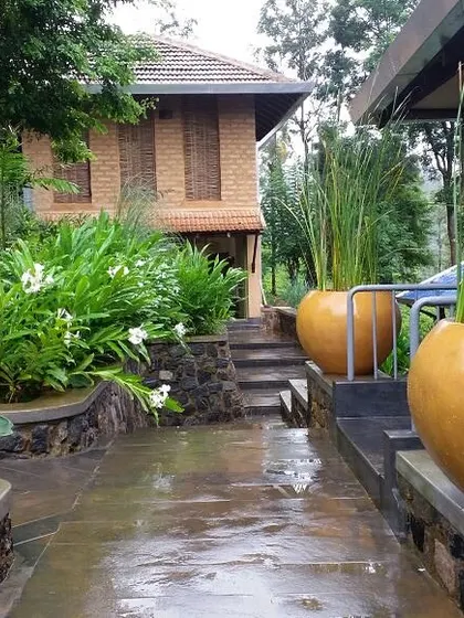The landscaped pathway at PLENTI House, where large terracotta pots and lush plants create a welcoming and vibrant atmosphere.
