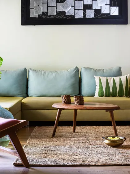 A minimalist living room setup with a clean-lined sofa, a jute rug, and abstract art, showing our versatility in different design styles.