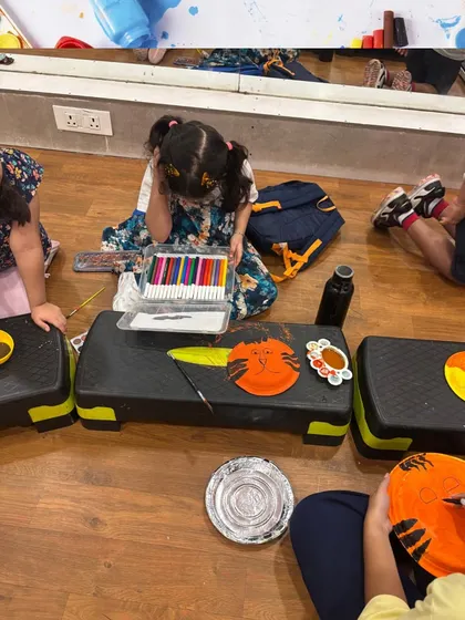 A young artist is completely absorbed in her work, painting a tiger face on a paper plate. Our classes provide a space for kids to focus and express their creativity.