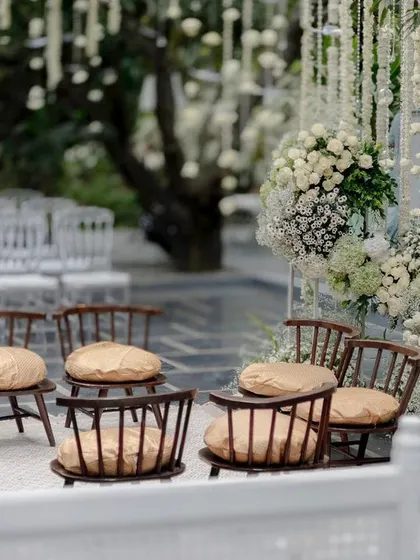 An intimate seating area at an all-white wedding, with chairs arranged amidst a sea of flowers.