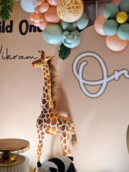 A life-sized plush giraffe prop stands tall next to the cake table, adding a wow-factor to this jungle party decor.