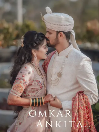 A tender moment between a newly married couple. The groom's gentle kiss on the bride's forehead is a classic expression of love.