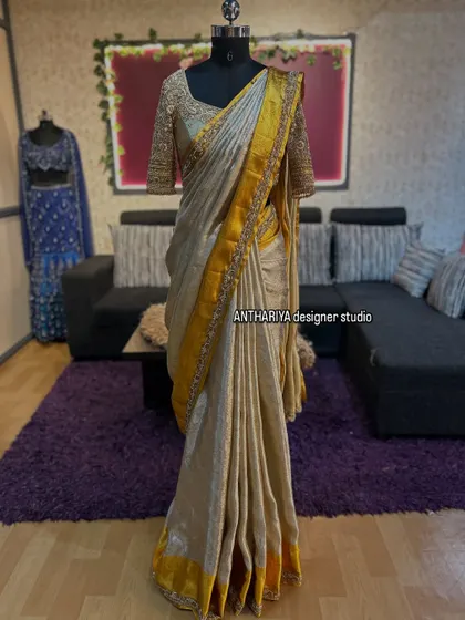 A stunning off-white and yellow Kanjivaram saree, pre-draped on a mannequin to showcase the full look with its embroidered blouse.