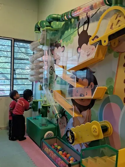 Two young students are fascinated by our interactive ball wall machine. I incorporate elements of sensory and discovery play into our centers to make learning a part of the fun.
