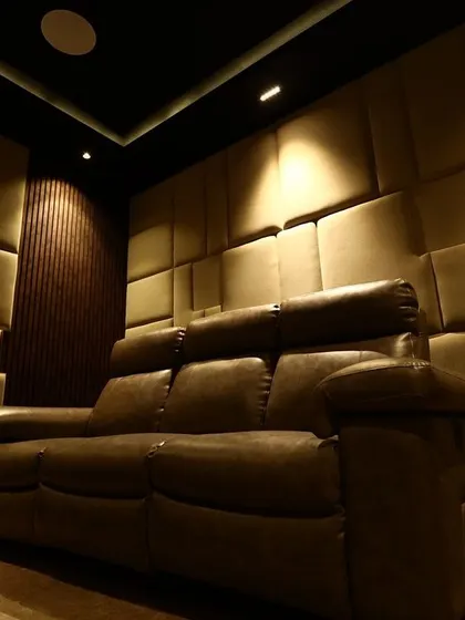 A low-angle shot of the back-row seating, highlighting the plush leather and the intricate, three-dimensional texture of the acoustic wall panels.