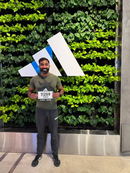 Posing with the race bib against the Adidas logo wall. The pre-race rituals are part of the whole experience.