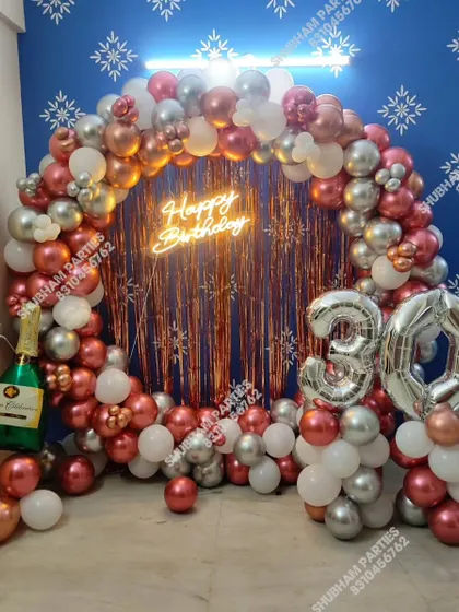 A glamorous 30th birthday celebration featuring a rose gold and silver balloon ring with a fringe backdrop and large number balloons.