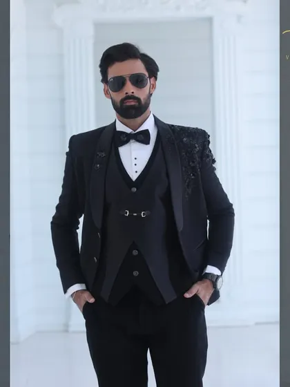 A confident pose in our custom black embroidered tuxedo. The three-piece set includes a matching waistcoat and is tailored to provide a sharp, commanding presence.
