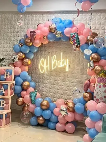 A beautiful "Oh Baby" gender reveal setup. The balloon ring is split between pink and blue colors, with rose gold accents and "BABY" blocks.